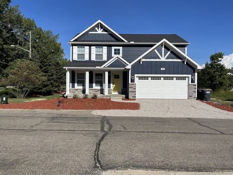 Charming two-story home with welcoming front porch, bright exterior, and spacious attached garage.