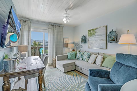 Settle into your bright coastal retreat with plush seating, beach-inspired decor, and a balcony view that invites relaxation.