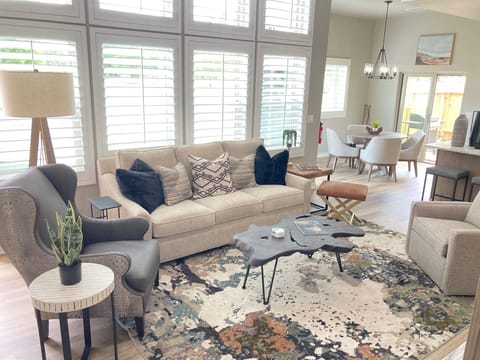 Large living area with television open to kitchen/dining and backyard.