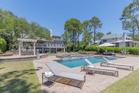 Lush landscaping surrounds a sparkling pool and elevated spa, paired with multiple lounge areas ideal for sunbathing, relaxing, or entertaining.