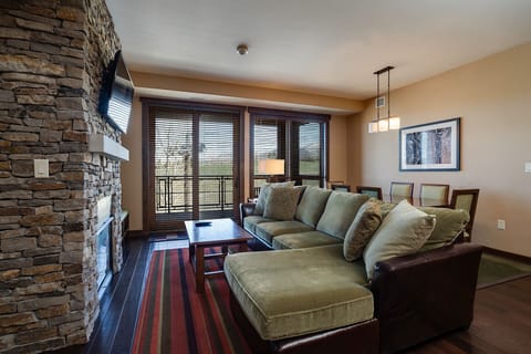 Sink into plush seating by your stone fireplace, where warm lighting and mountain views create the perfect evening retreat.