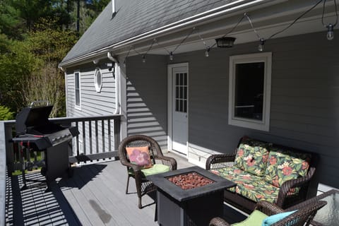Outdoor deck extending off the back, with fire pit, grill, and ambient lighting.