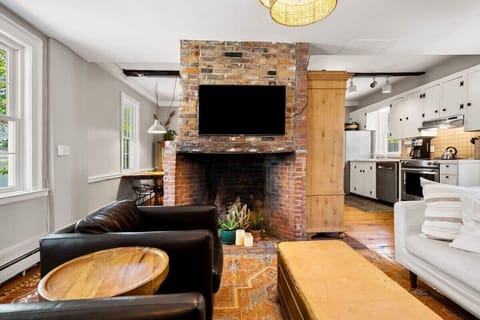 Living room with smart TV, couch, accent chairs and dedicated "work-from-home" desk. The fireplace is inoperable.