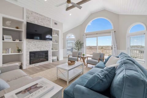 The large living area is open concept, has cathedral shiplap ceiling, wood beams, two couches, chairs, an electric fireplace and a 65 inch LG Smart TV to watch your favorite shows and movies. Easy access to deck and hot tub to listen to the ocean.
