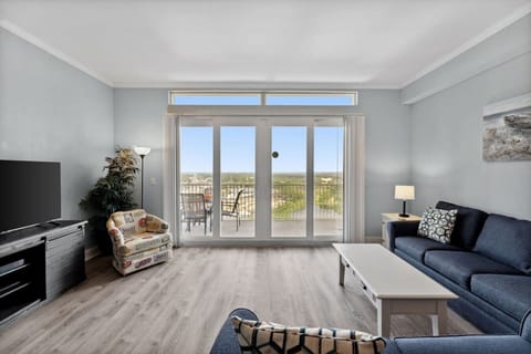 Living room with flat screen TV, fold out sofa and view to furnished balcony