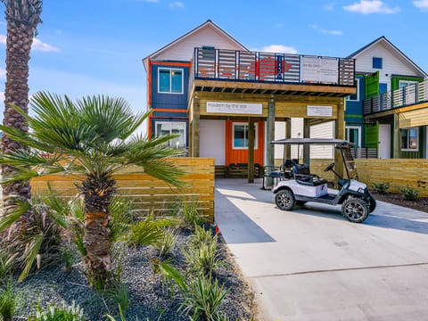 Colorful modern beach houses with tropical landscaping and golf cart parking create a vibrant coastal retreat atmosphere.