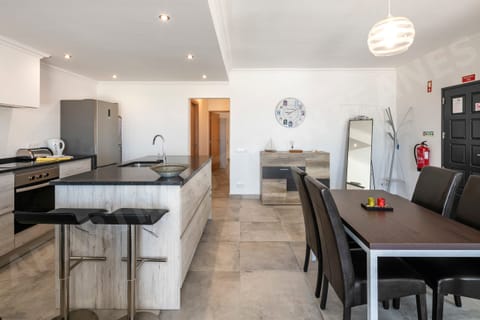 Spacious open-plan kitchen and dining area with modern appliances, sleek design, and a large dining table ideal for family meals.