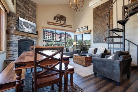 Relax in your mountain retreat with stone fireplace, cozy seating, and scenic views through expansive windows.