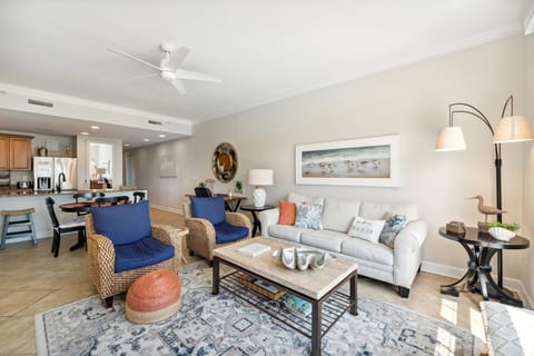 The living room offers ample, comfortable seating, a large flat screen television, door to the unit's private balcony, and breathtaking views of the Nicklaus designed golf course & Grand Lagoon.