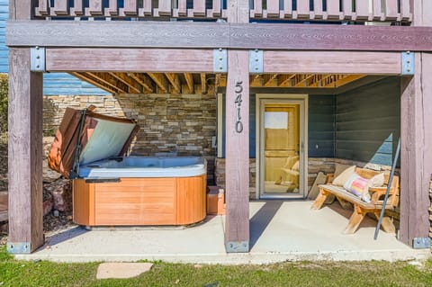 Step onto your private patio where a bubbling hot tub awaits under a wooden pergola. Unwind with beach views, cozy seating, and direct access to your sun-soaked retreat.