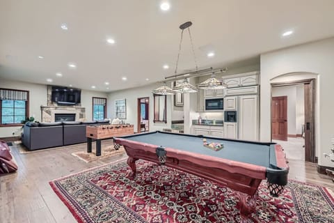Welcome to the downstairs living room, a perfect blend of fun and relaxation! Enjoy a game of pool or foosball, cozy up by the gas fireplace, and whip up snacks in the kitchen with fridge. Easy access to the inviting hot tub for ultimate unwinding!