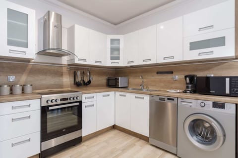 A modern kitchen with white cabinets, built-in appliances.