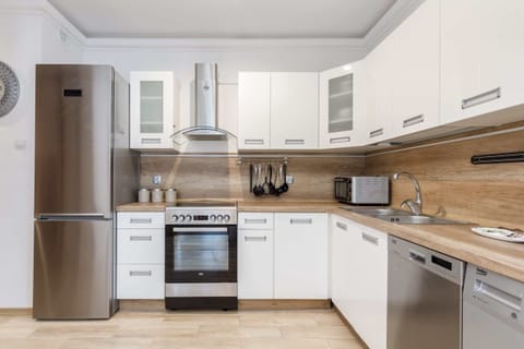 A modern kitchen with white cabinets, built-in appliances.