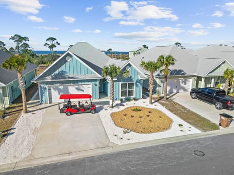Modern coastal property featuring tropical landscaping and convenient golf cart parking in a peaceful neighborhood setting.