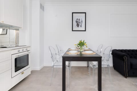 A dining area with a sleek black table, transparent chairs, and vibrant decor, creating a contemporary vibe.
