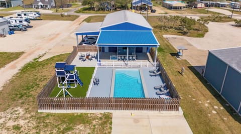 Aerial of Pool, Outdoor Kitchen with Bar, His/Her Half-Bathrooms and Playscape