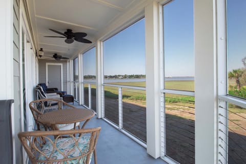 Relax on your private screened porch with ceiling fans, cozy seating, and breathtaking water views stretching across peaceful marshlands and coastal scenery.