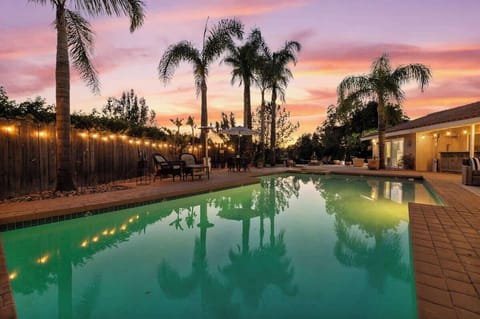 Paradise at sunset! Unwind by the shimmering pool, surrounded by swaying palm trees and glowing string lights, as the sky paints a breathtaking masterpiece. A perfect setting for peaceful evenings and unforgettable gatherings.