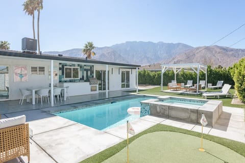 Sun-soaked pool w/ lounge chairs, palms & mountain backdrop for easy desert days.