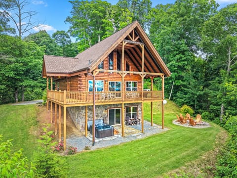 Elevated view of a log cabin surrounded by mature trees with a wraparound deck and open yard. A peaceful Bryson City cabin tucked into the Smoky Mountains for a private mountain getaway.