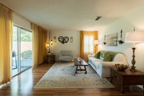 Living room with natural light, warm yellow curtains, and classic wooden furniture.