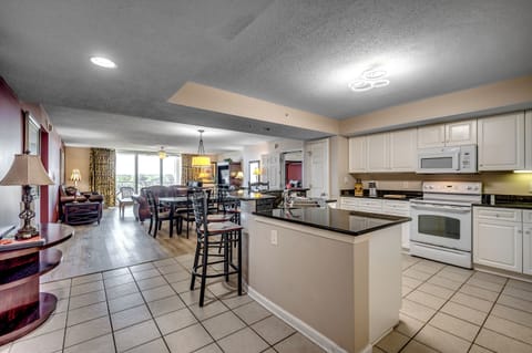 Open kitchen with breakfast bar and sleek tile flooring