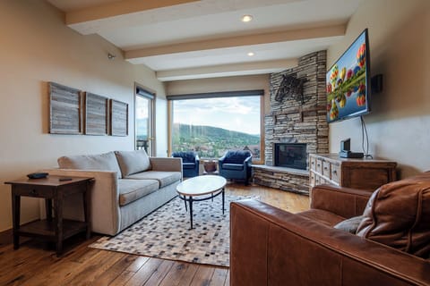 Unwind in your spacious living room with stunning mountain views, cozy fireplace, and comfortable seating perfect for relaxing evenings.