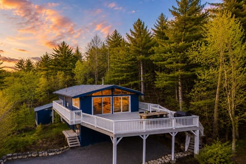 Exterior of the home at sunset with the wraparound deck and wooded setting
