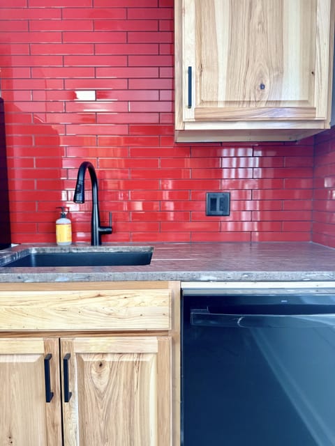Red glass tile contrasts light hued hickory and pressure-formed rock countertops