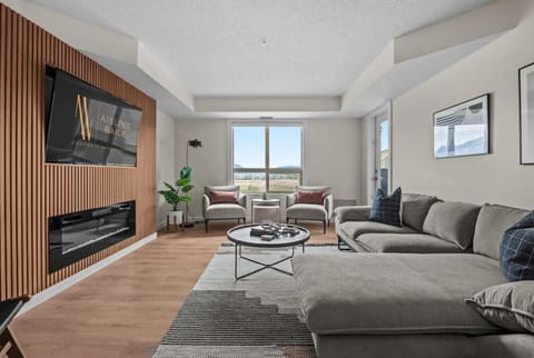 Living room with a 65` Smart TV, cozy seating options, an electric fireplace and access to the large private balcony.