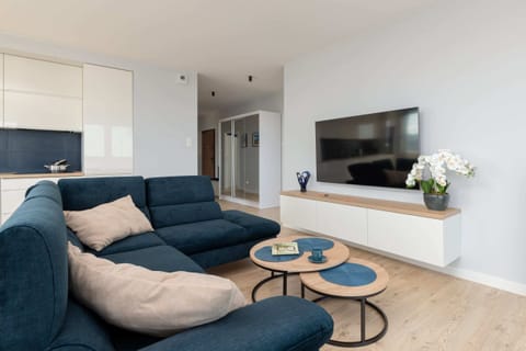 A bright and open living area featuring a large blue sectional sofa, a coffee table, and modern decor.