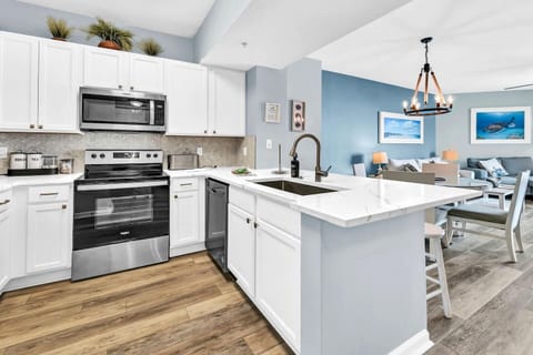 Modern kitchen w/ white cabinetry, island seating, & full-size appliances for easy meals