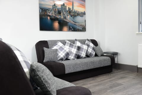 Sophistication in your living room! Featuring a plush gray sofa, chic chequered throw pillows, and a captivating hanging painting that adds a touch of elegance to your stay.