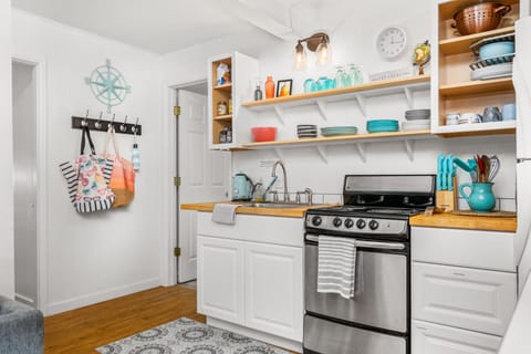 Simple kitchen with microwave + stove + fridge + cookware/dishes.