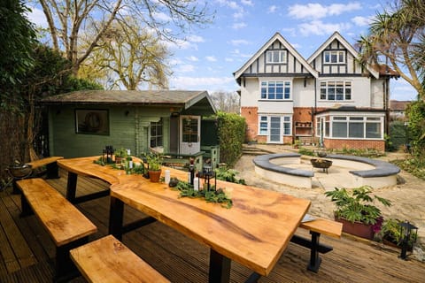 Garden with fire pit, large seating area, stunning dining table, and summer house with fridge and serving hatch
