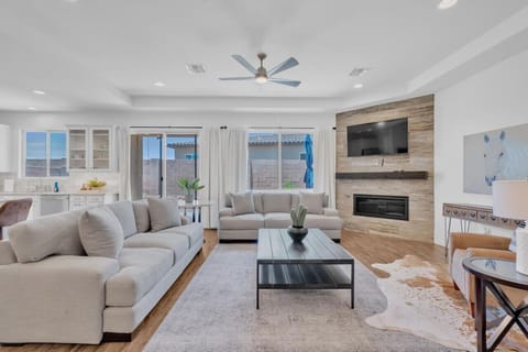 Grand living room with gas fireplace, smart TV, and 10-ft ceilings, open to kitchen and dining area and flooded with natural light