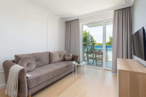 A spacious living room featuring a comfortable sofa, TV and access to balcony.