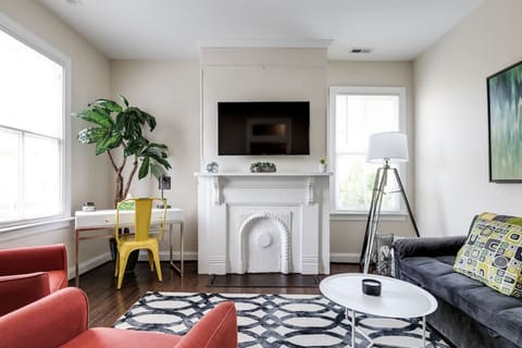 Stylish, cozy living room featuring a flat‑screen Roku TV, full‑size pull‑out sofa, seating for four, and a convenient desk area — perfect for relaxing or getting a little work done.