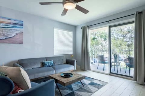 Bright living room with a gray sofa, coffee table, and sliding glass doors opening to the patio.
