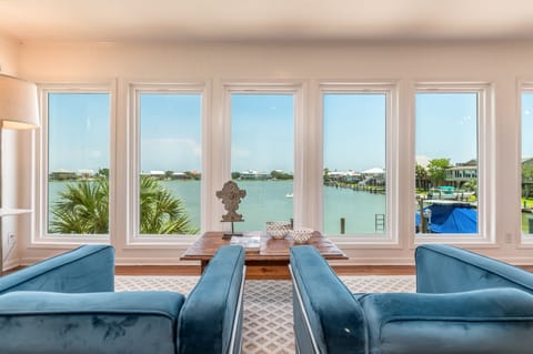 Enjoy breathtaking waterfront views from this cozy sitting area with plush seating and floor-to-ceiling windows, bringing in natural light and stunning Dauphin Island scenery.
