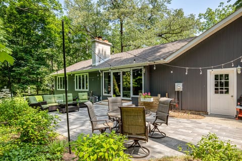 Spacious backyard patio w/ outdoor dining set, surrounded by mature trees for peaceful gatherings.