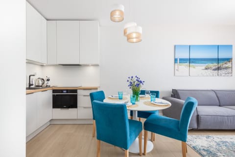 A modern living area with a wall-mounted TV, adjacent to the dining space, offering a comfortable spot to relax.