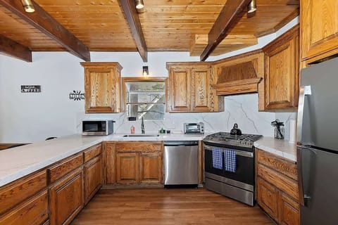 Kitchen with stove, oven, fridge/freezer, toaster oven, microwave, tea kettle, and coffee maker.