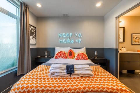 Modern bedroom with neon sign and cozy bedding
