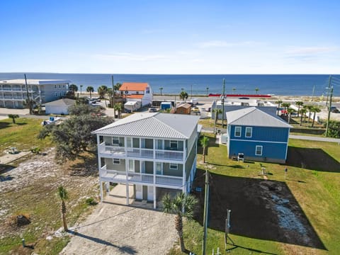 Elevated coastal property with panoramic views of the Gulf, featuring multiple decks and prime beachfront location among colorful beach houses.