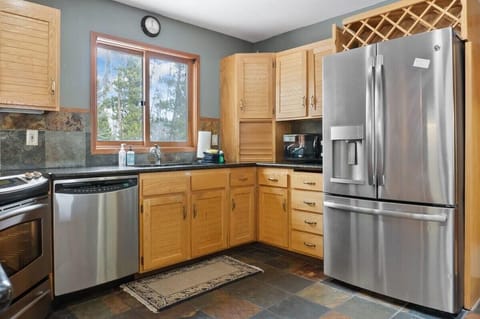 The fully equipped kitchen features a pass-through window to the dining room, stainless steel appliances, spacious countertops, and all the cookware needed to whip up a delicious meal.