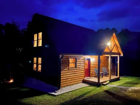 Billabong Cabin glowing under the night sky.   When pulling in look for the  black roof, red door, and the feeling of nature calling you in.