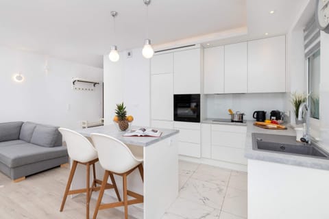 A cozy dining corner with a table for two, adorned with snacks and beverages for a welcoming atmosphere. A basket of amenities is placed thoughtfully in the background.