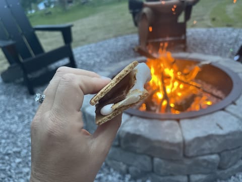 Handcrafted fire pit accompanied by comfortable Adirondack chairs, perfect for gathering around and enjoying the classic delight of roasting s'mores.