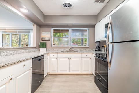 The kitchen is a masterpiece of sleek, modern design, boasting a sophisticated silver, black, and white color scheme.